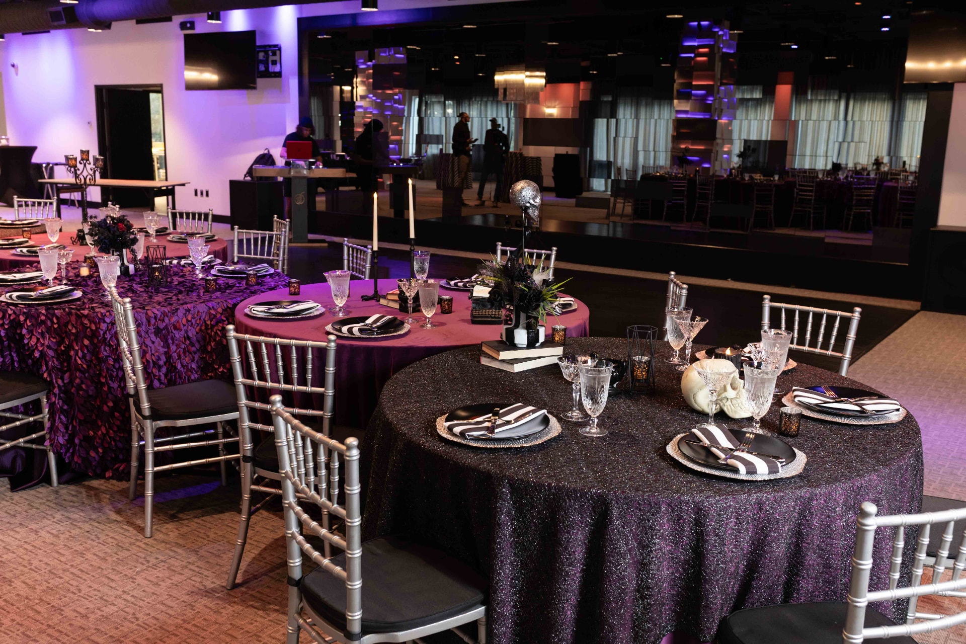 Round tables dressed in plum and black linens alongside the dance floor at The MEZZ