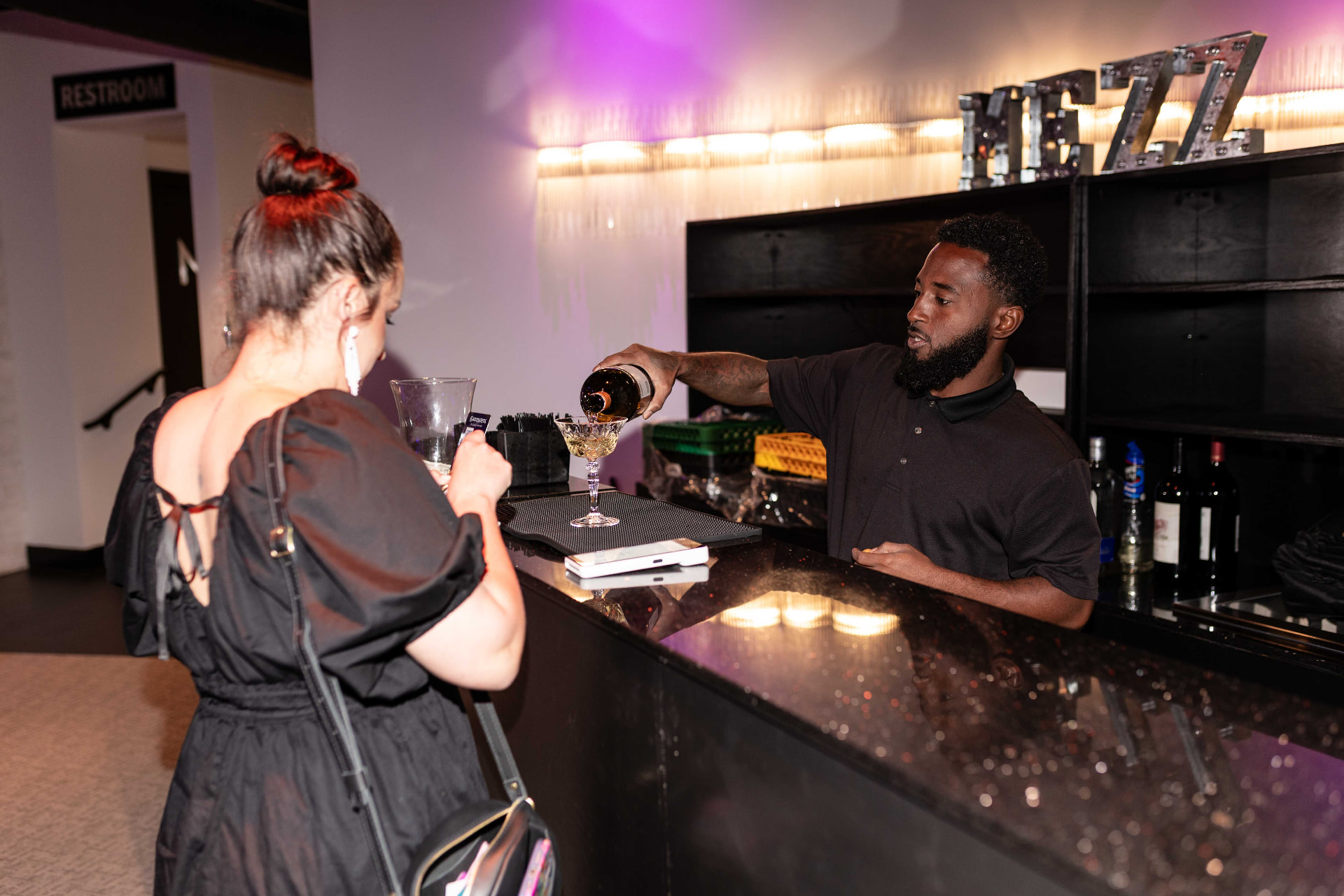 A bartender pouring a drink for a guest at the built-in bar at The MEZZ